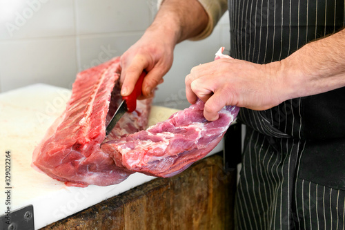 Butcher slicing a raw pork fillet off the bone