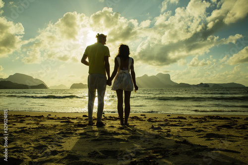 young couple on the sunset time at the beach holding their hands