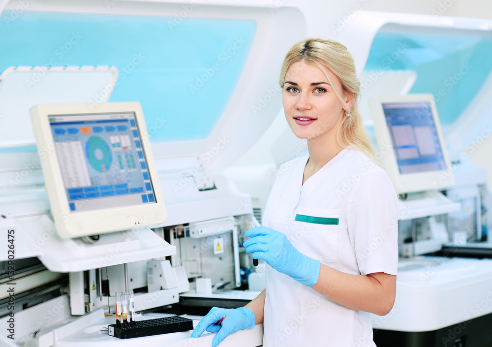 a female scientist near the analyzer in a medical microbiological laboratory. Equipment for analysis, DNA, PCR a female scientist near the analyzer in a medical microbiological laboratory. Equipment for analysis, DNA, PCR