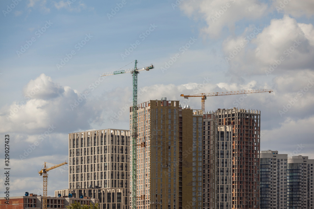 Construction site with cranes against the cloudy sky