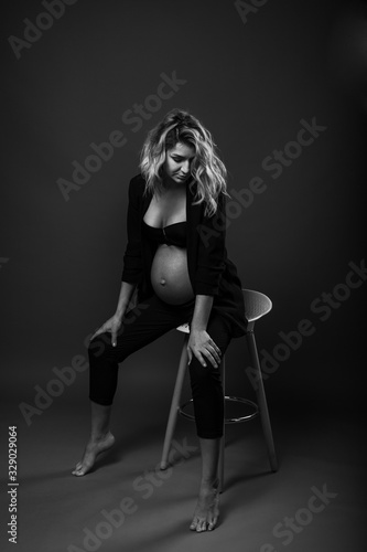 vertical portrait of a young pregnant woman on gray background