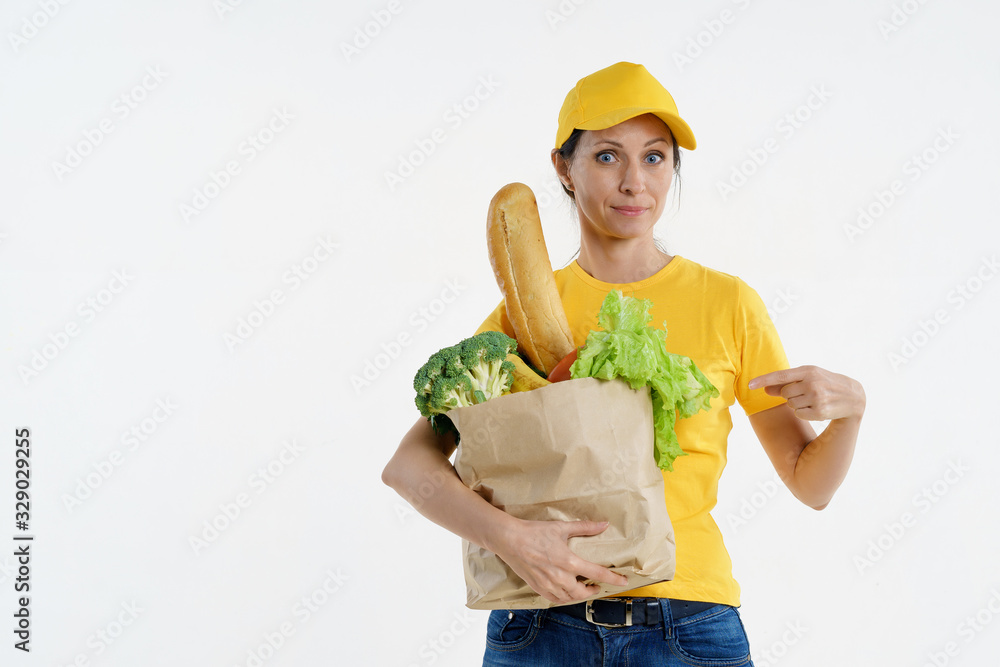 Happy delivery woman pointing at grocery bag in hand Happy delivery woman pointing at grocery bag in hand
