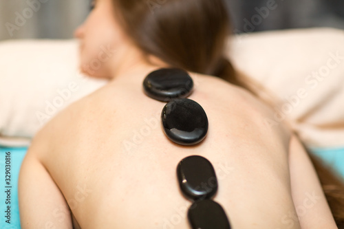 Young beautiful woman and stone massage in beauty spa