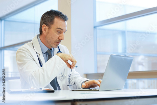 Doctor in hospital office working on laptop
