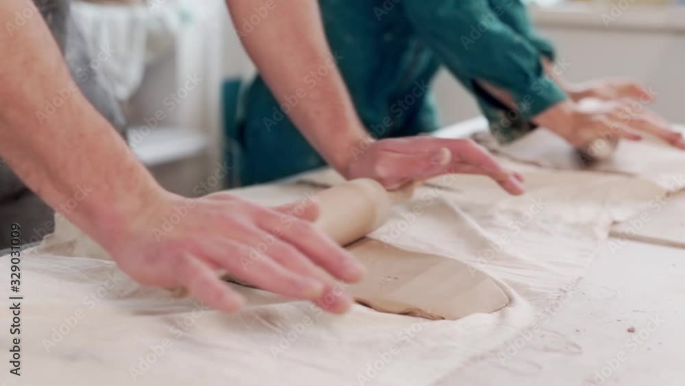 man and woman roll out clay on the table man and woman roll out clay on the table