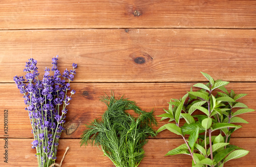 gardening, ethnoscience and herbs concept - bunches of lavender, dill and peppermint on wooden background