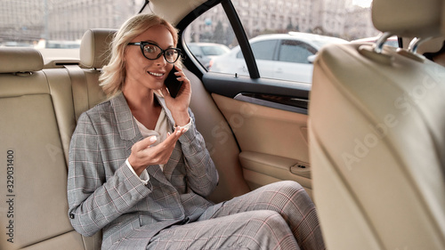Great news. Happy businesswoman in classic wear sitting in the car and talking by the phone with her business partner © Svitlana