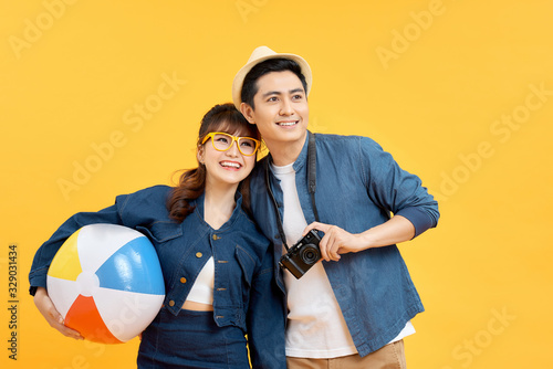 Playful Asian couple in summer casual clothes with beach accessories studio shot isolated