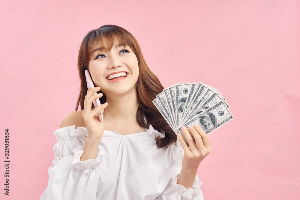 Image of a shocked surprised screaming young pretty woman posing isolated over pink wall background using mobile phone holding money. Image of a shocked surprised screaming young pretty woman posing isolated over pink wall background using mobile phone holding money.