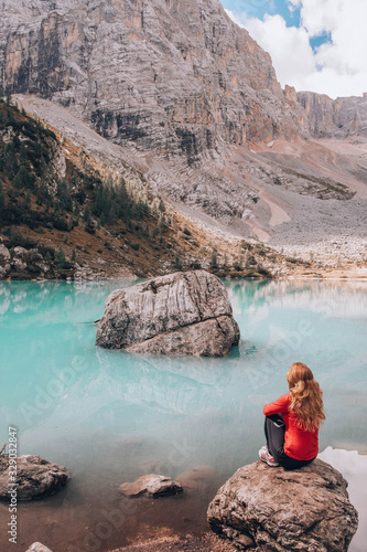 Young woman sitting on a huge rock in Lake the Sorapis in italian Alps / Lago di Sorapiss photo