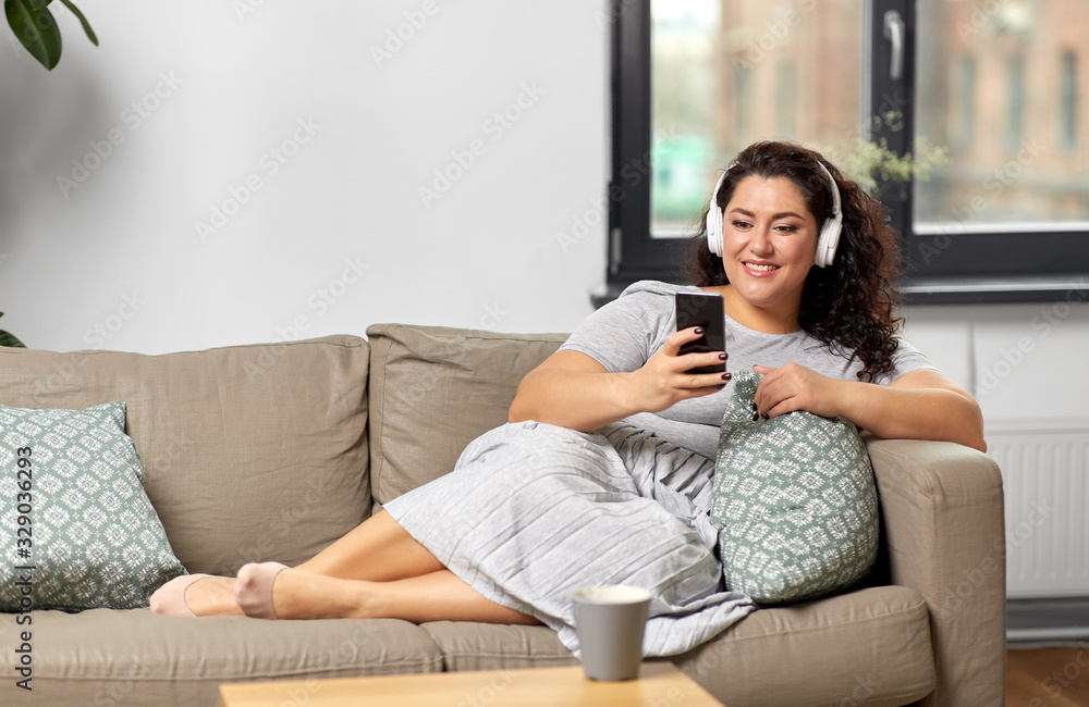 technology, people and leisure concept - happy young woman in headphones listening to music on smartphone at home technology, people and leisure concept - happy young woman in headphones listening to music on smartphone at home