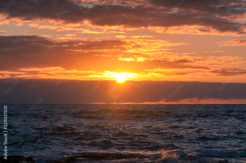 Ocean sunrise scene with waves and bright orange sky