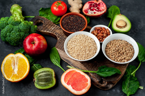 Selection of healthy food   fruits  seeds  cereals  superfoods  vegetables  leafy vegetables on a stone background. Healthy food for humans