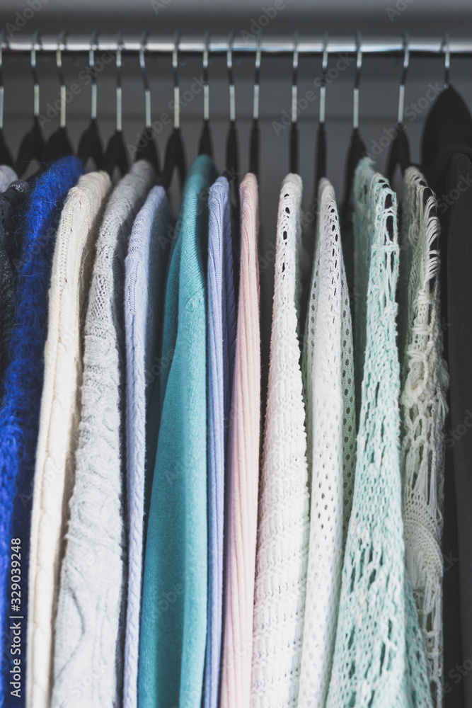 organizing and tidying up conceptual still-life, wardrobe with tidy selection of different knits lined up on black flocked hangers organizing and tidying up conceptual still-life, wardrobe with tidy selection of different knits lined up on black flocked hangers