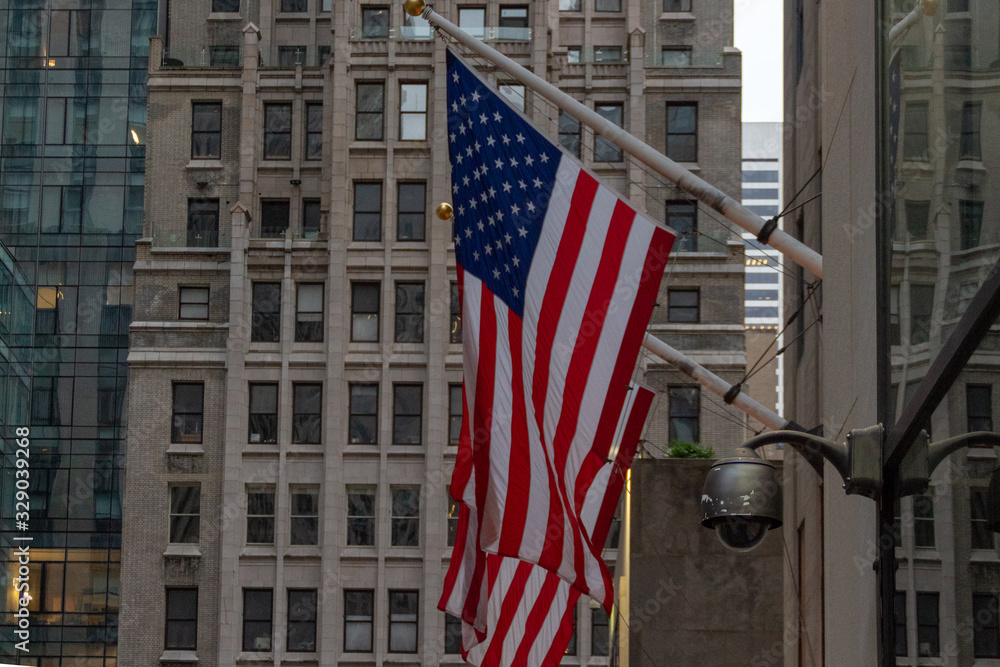 Four American Flags Waving On Flagpoles Protruding From Side of Building in New York City