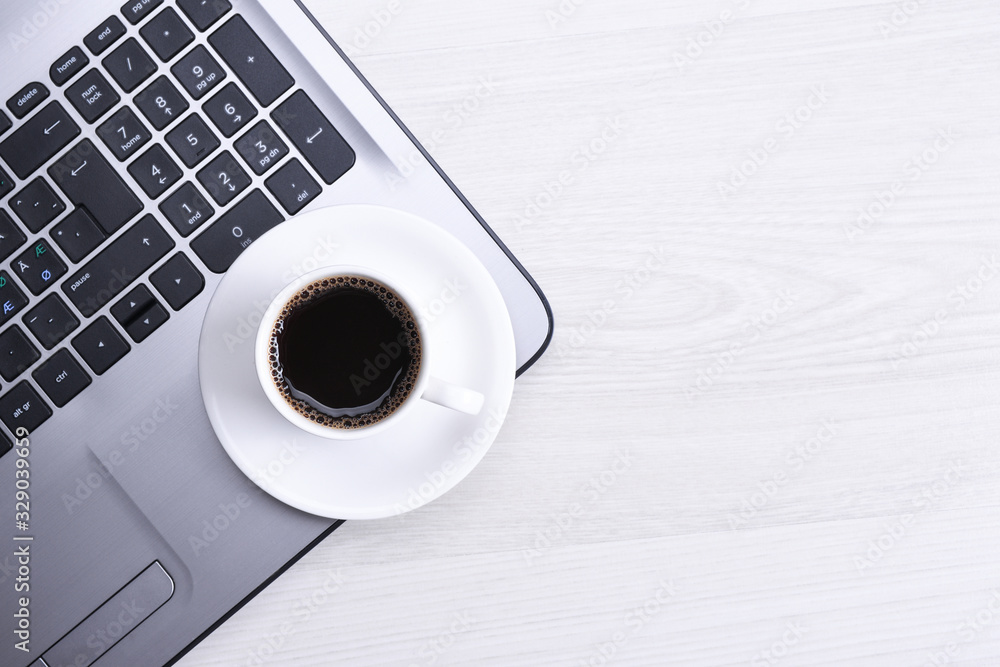 Cup of coffee on laptop keyboard on the wooden desk table.Top view, flat lay. With copy space and place for text. Cup of coffee on laptop keyboard on the wooden desk table.Top view, flat lay. With copy space and place for text.