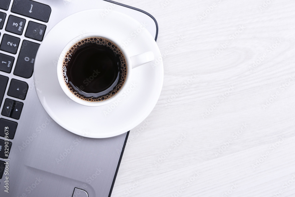 Cup of coffee on laptop keyboard on the wooden desk table.Top view, flat lay. With copy space and place for text. Cup of coffee on laptop keyboard on the wooden desk table.Top view, flat lay. With copy space and place for text.