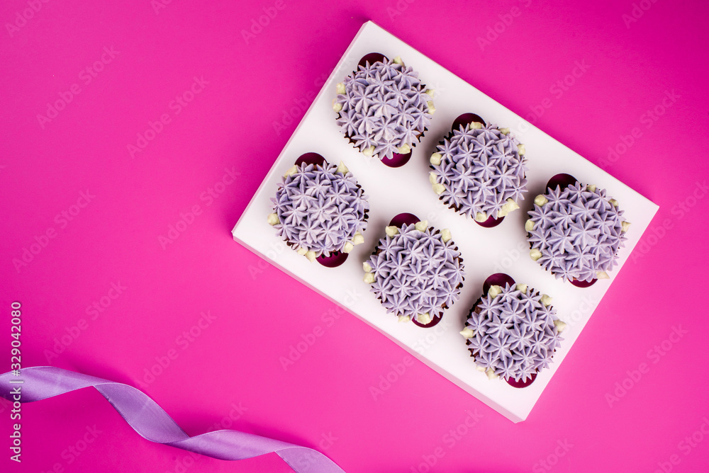 Delicious shawn cupcakes with curd cream in the form of flowers on a pink background.