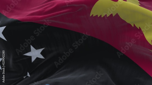 4k Papua New Guinea National flag slow loop seamless waving with visible wrinkles in wind blue sky background.A fully digital rendering;animation loops at 20 seconds. photo