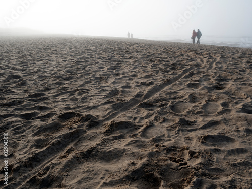 Footprints in the sand of the seashore. Light fog.