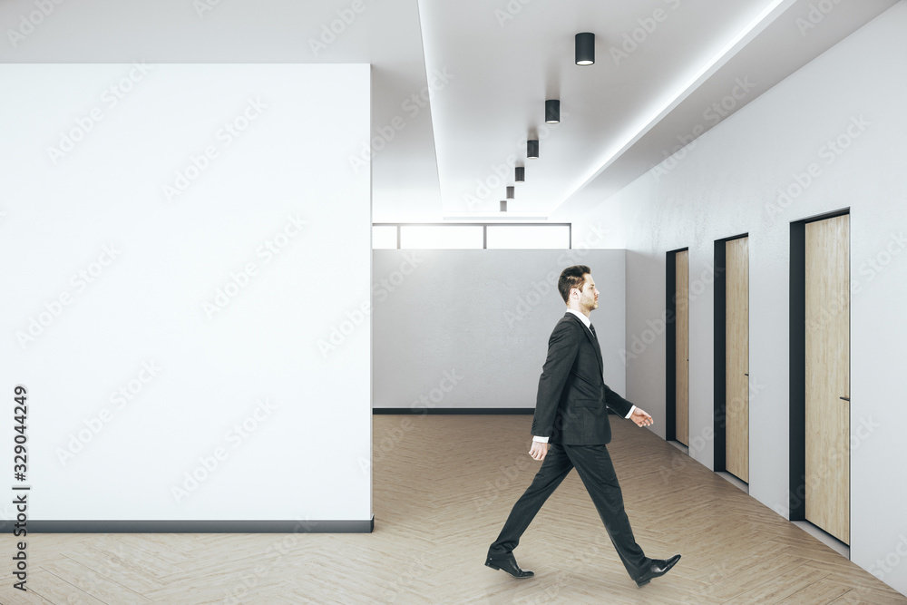 Businessman walking in hall interior with blank wall. Businessman walking in hall interior with blank wall.