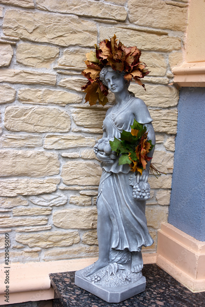 Fototapeta premium Young woman sculpture with autumnal leaves. Queen of autumn.