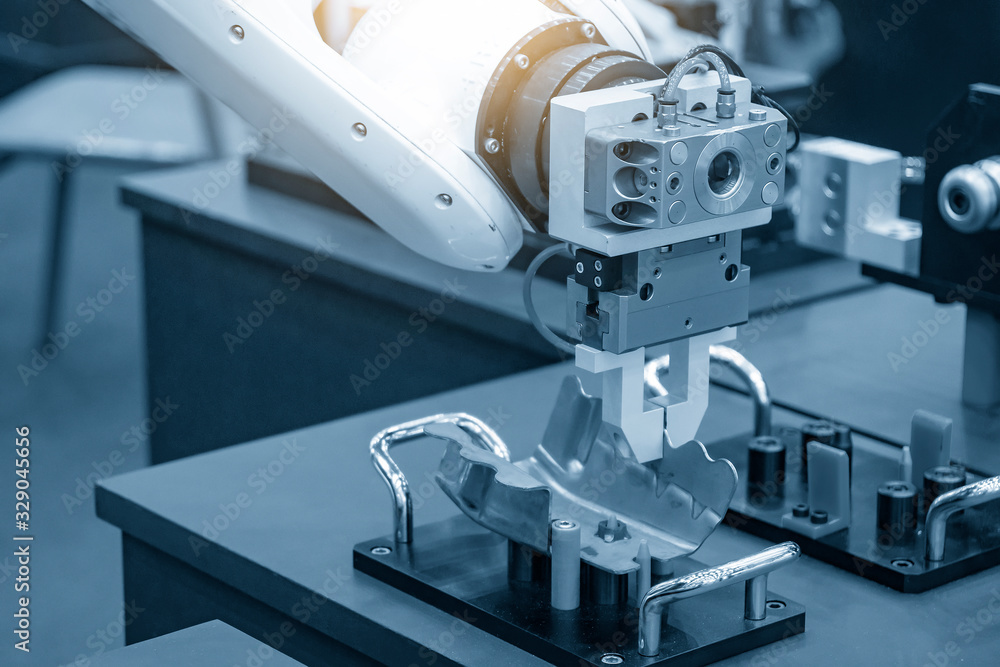 The robotic arm gripping the formed sheet metal parts from the setting jig  to the conveyor belt in automotive factory. The hi-technology material  handing process in by robotics system. Stock-foto | Adobe