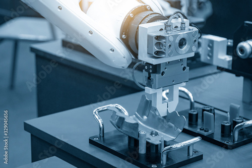 The robotic arm gripping the formed sheet metal parts from the setting jig to the conveyor belt in automotive factory. The hi-technology  material handing process in by robotics system. photo
