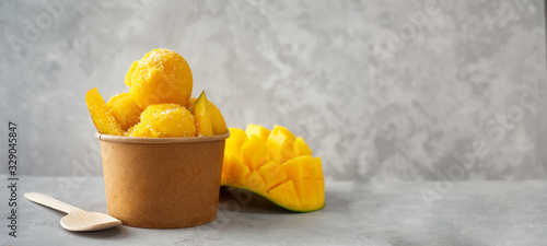 Refreshing mango ice cream in craft paper cup on gray background photo