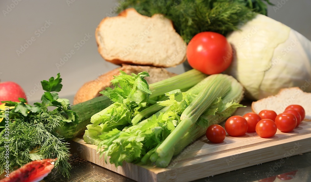 Still life from fresh vegetables and bread: celery, tomatoes, greens, cabbages