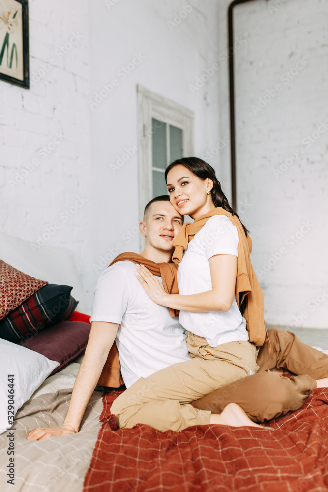 Beautiful couple on the bed. Love story in the interior Studio. Happy and laughing people. At home, having fun on the bed.