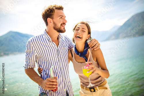Beautiful couple having fun on the beach, drinking cocktails and smiling.