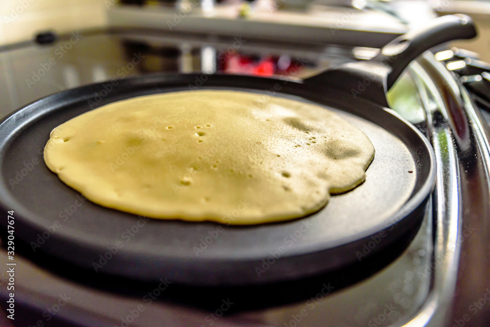 pancake frying pan with crepe pancake cooking on cooker in kitchen pancake frying pan with crepe pancake cooking on cooker in kitchen