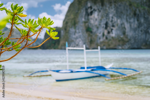 El Nido. Defocused traditional filippino boat on shore with Pinagbuyutan island in background. Palawan, Bacuit archipelago, Philippines photo