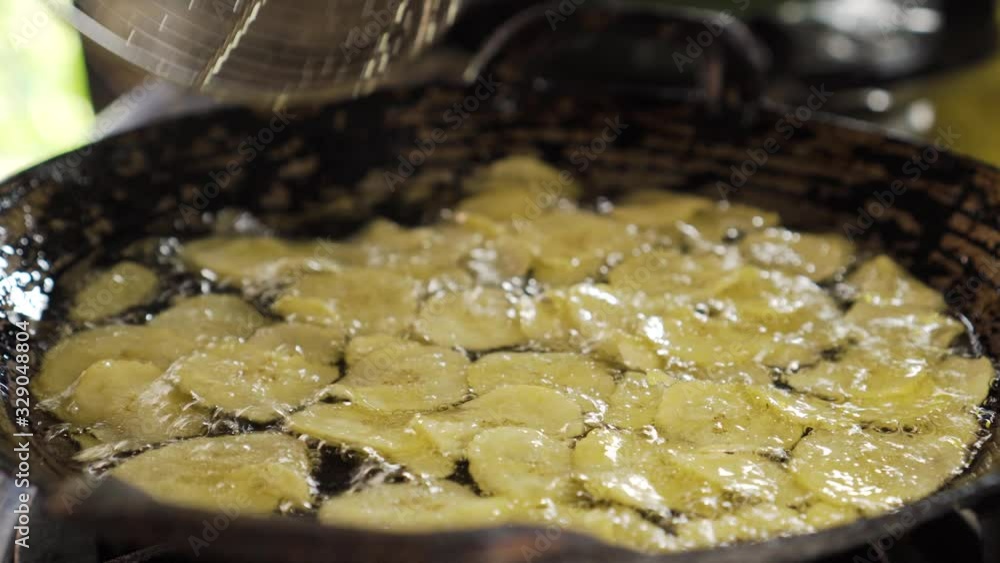 Pieces of banana get frying on a pan full of oil.Making of Sweet Banana Crisp. Thai Dessert. fat. Pieces of banana get frying on a pan full of oil.Making of Sweet Banana Crisp. Thai Dessert. fat.