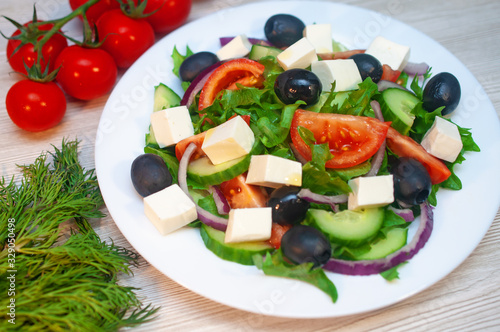 Greek salad with tomatoes, cucumbers and feta cheese with olives on the table