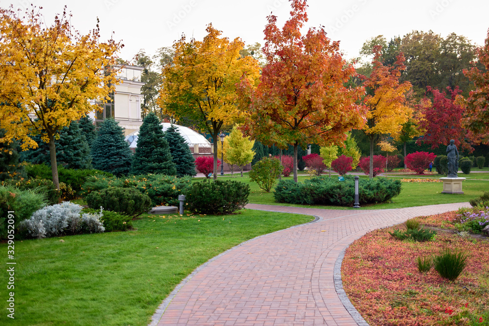 Well-groomed autumnal city park. Cobblestone pathways and colorful trees.