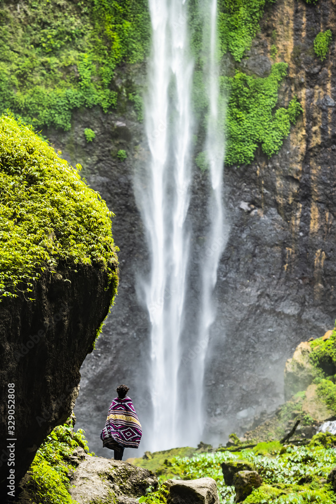 Stunning view of a tourist enjoying the view of the Tumpak Sewu Waterfalls. Tumpak Sewu Waterfalls also known as Coban Sewu are a tourist attraction in East Java, Indonesia. Stunning view of a tourist enjoying the view of the Tumpak Sewu Waterfalls. Tumpak Sewu Waterfalls also known as Coban Sewu are a tourist attraction in East Java, Indonesia.
