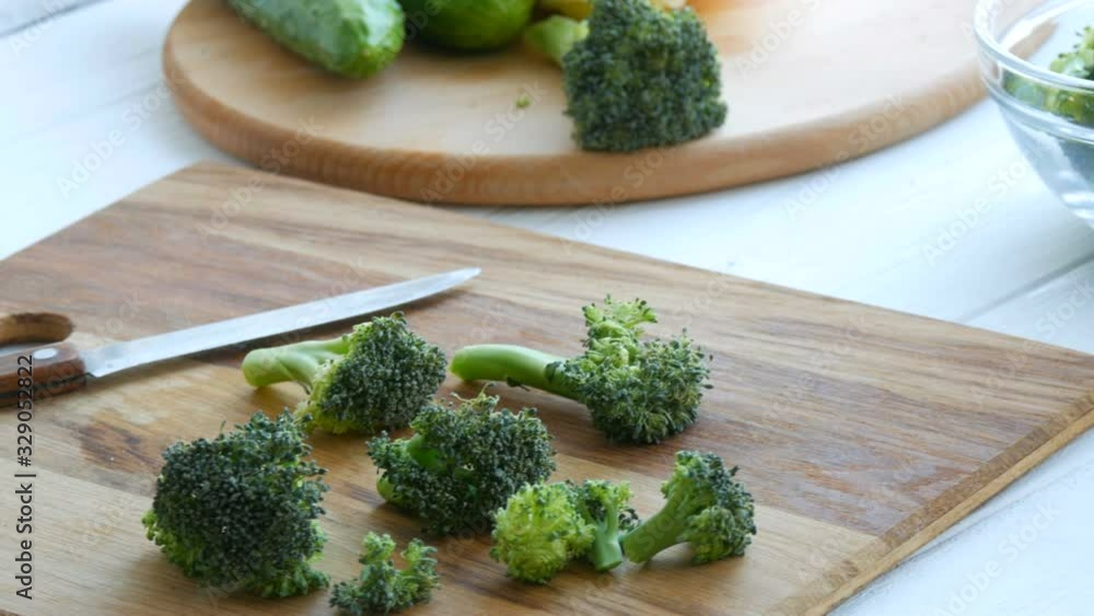 Cut raw fresh green broccoli cabbage on a kitchen board. Cook cut vegetables with a knife. Vegan food Cut raw fresh green broccoli cabbage on a kitchen board. Cook cut vegetables with a knife. Vegan food