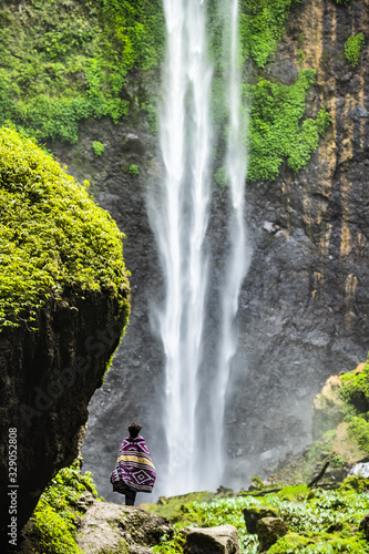Stunning view of a tourist enjoying the view of the Tumpak Sewu Waterfalls. Tumpak Sewu Waterfalls also known as Coban Sewu are a tourist attraction in East Java, Indonesia.