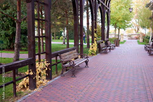 Empty wooden benches in a park. Cobblestone walkway floor. © DenisProduction.com