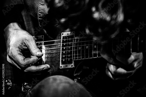 Hands playing on a guitar in a concert on a stage in a club