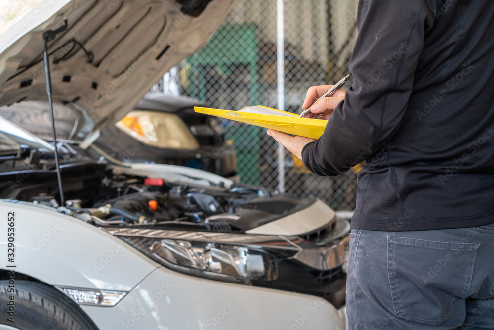 Yellow folder service report working in hand of mechanic man, car service maintenance and repair garage Yellow folder service report working in hand of mechanic man, car service maintenance and repair garage
