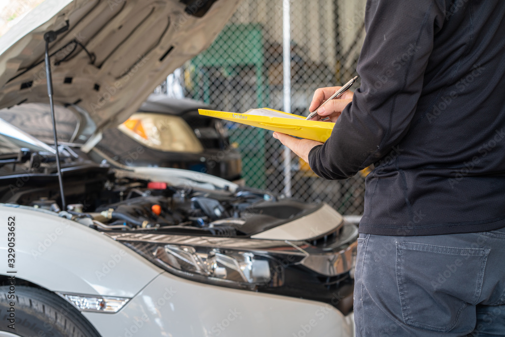 Yellow folder service report working in hand of mechanic man, car service maintenance and repair garage