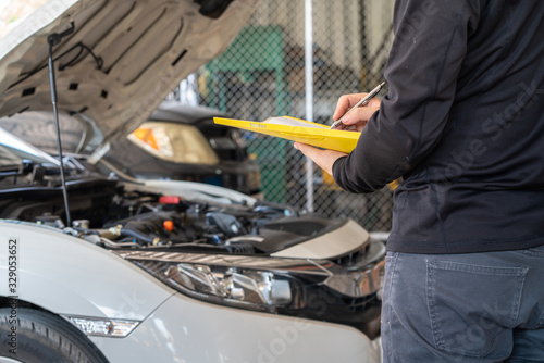 Yellow folder service report working in hand of mechanic man, car service maintenance and repair garage