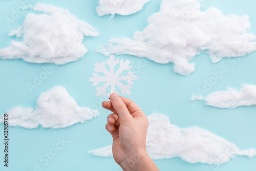 Child holding a cut out showflake on blue sky background photo