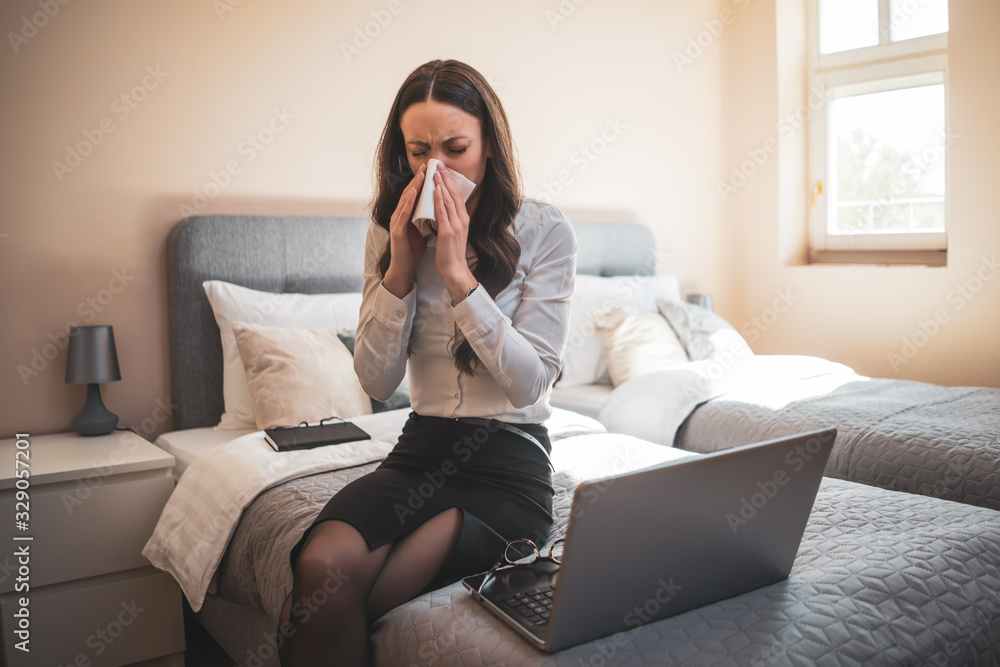 Overworked businesswoman on business trip sitting in hotel room and working on laptop. She is having allergy. Overworked businesswoman on business trip sitting in hotel room and working on laptop. She is having allergy.