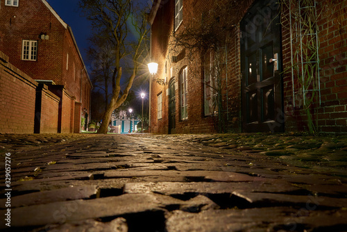 frog perspective of a cobble stone footpath next to the historic house of the museum of navigation in Brake  Unterweser   Germany - construction year of the brick house is written at the door  1808 