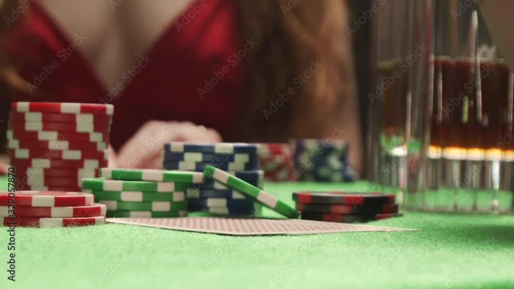 Player checking his poker hand. Pair of aces. On the background is woman in red Player checking his poker hand. Pair of aces. On the background is woman in red