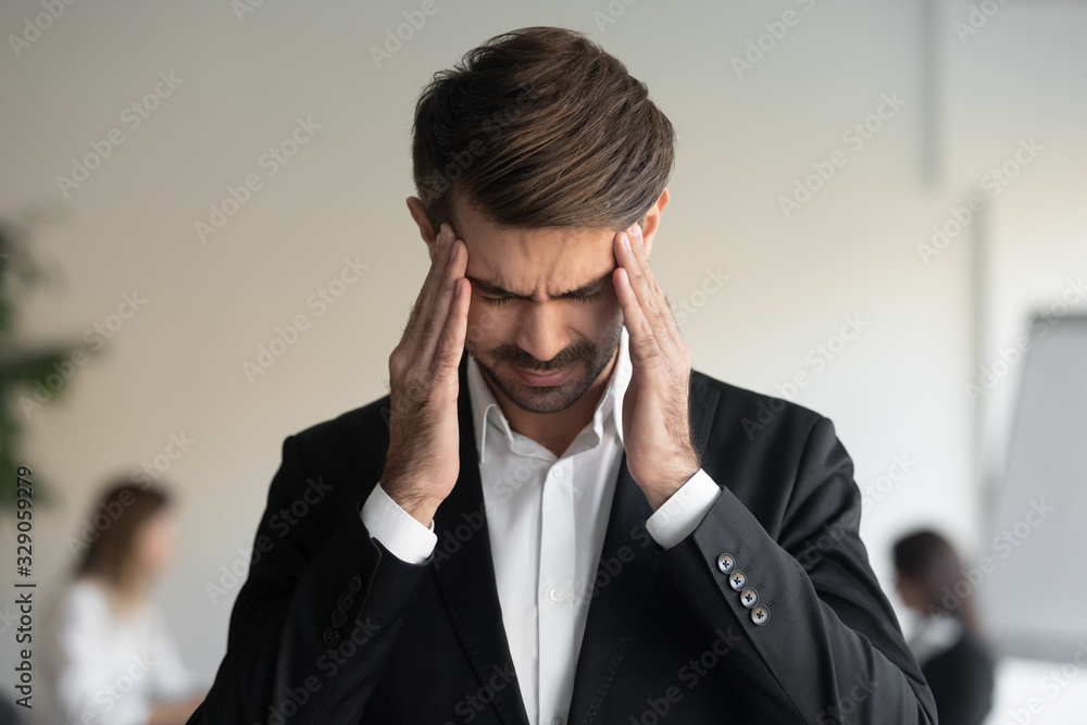 Stressed millennial overwhelmed businessman suffering from migraine head shot close up portrait. Exhausted unhealthy young office worker employee massaging temples, feeling strong head ache. Stressed millennial overwhelmed businessman suffering from migraine head shot close up portrait. Exhausted unhealthy young office worker employee massaging temples, feeling strong head ache.